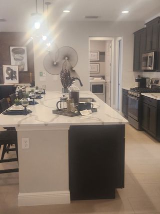 A modern kitchen featuring sleek black cabinetry, a spacious island, and stylish decor with artful lighting.