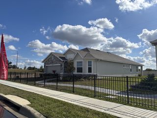 Street view A charming light-colored home with a stone accent facade in Highfield at Twisted Oaks by Park Square Residential (Wildwood, FL).