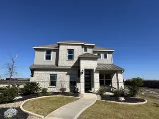 Street view A charming two-story home with modern finishes and a well-maintained lawn in Dauer Ranch by Brightland Homes (New Braunfels, TX).