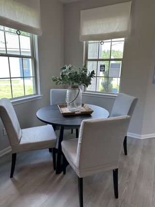 Model Home A cozy dining nook featuring a round table, upholstered chairs, and natural light from two large windows.