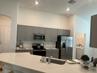 A modern kitchen featuring sleek grey cabinets, stainless steel appliances, and a spacious white countertop.