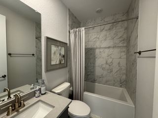 Model Home A modern bathroom featuring marble-patterned tiles, sleek fixtures, and elegant artwork for a sophisticated touch.
