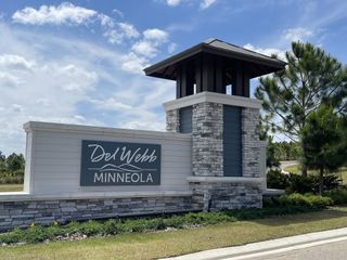 A grand entrance sign welcomes residents to Del Webb Minneola, featuring elegant stonework and lush landscaping in Minneola, FL.