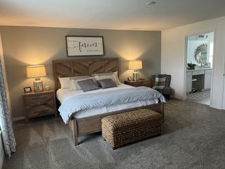 Model Home Cozy bedroom featuring a wooden bed, plush carpeting, and soft lighting, with a stylish entrance to an elegant bathroom.