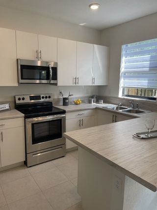A modern kitchen with sleek white cabinetry, stainless steel appliances, and ample natural light.
