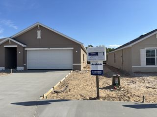 A modern beige home with a two-car garage under sunny skies in Autumn Glen by D.R. Horton (Belleview, FL).