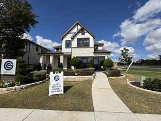 A stunning modern farmhouse-style home with stone and stucco finishes. The neatly landscaped front yard and signage indicate quick move-in homes available in this beautiful Parmer Ranch community by GFO Homes in Georgetown.