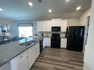 Model Home A stylish kitchen featuring a large island, black appliances, and granite countertops blending function with elegance.