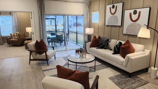 A sophisticated living room with neutral furnishings, bold accent pillows, and large windows opening to an outdoor patio.