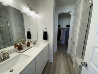 A modern bathroom with elegant dual sinks, sleek fixtures, and a spacious walk-in closet.
