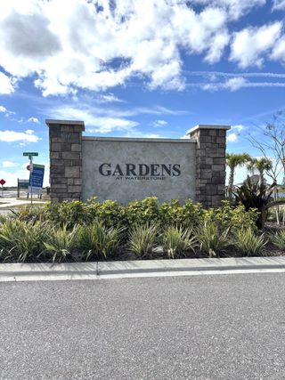 Welcome sign surrounded by lush greenery in Gardens at Waterstone I by KB Home (Palm Bay, FL).