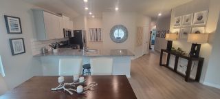 A stylish open-concept kitchen with granite countertops, white cabinets, and sleek stainless steel appliances.