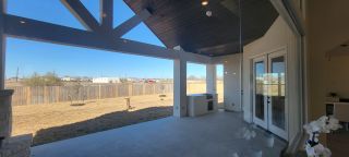 Model Home A spacious covered patio with exposed beams, clean lines, and large glass doors opens to a fenced yard.