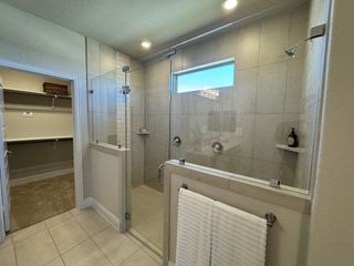 A spacious bathroom with a glass-enclosed shower, modern tiles, and a convenient walk-in closet.