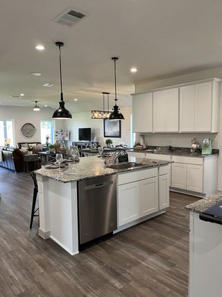 A modern kitchen with a central island, sleek granite countertops, pendant lighting, and open concept living area.