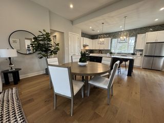 Open-concept dining and kitchen with round table, sleek white cabinetry, and elegant pendant lighting.