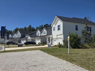 Street view A charming row of modern white homes with lush landscaping in Beacon Lake by Dream Finders Homes (St. Augustine, FL).