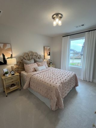 A beautifully decorated bedroom with soft pink bedding, rattan headboard, and large window for natural light.