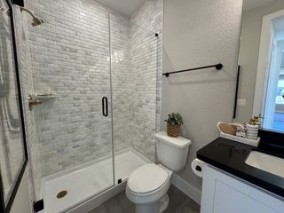 A sleek bathroom features a subway-tiled shower, modern fixtures, and elegant black countertop accents.