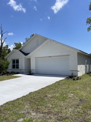 Street view A modern white home with a clean driveway and green lawn in Citrus County Spot Lots by D.R. Horton (Citrus Springs, FL).