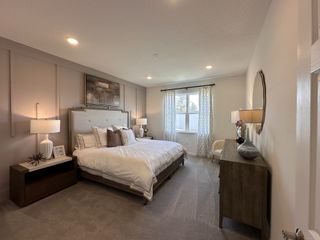 A cozy bedroom with a plush bed, elegant lamps, and soft carpet, featuring earthy tones and modern decor.