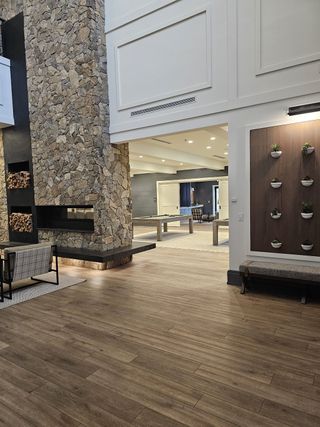 A grand clubhouse entrance showcasing a dramatic stone fireplace, modern accents, and wood flooring for a sophisticated ambiance.