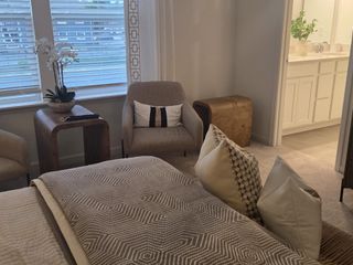 Model Home A cozy master bedroom with soft carpeting, a modern dresser, and a stylish seating area by the window.