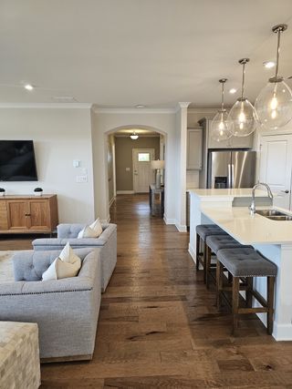 A cozy living space with plush seating, hardwood floors, and a modern kitchen with stylish lighting fixtures.