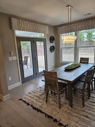 Model Home A bright dining area with a rustic wood table, contemporary chandelier, and patio access for seamless indoor-outdoor living.