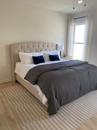 A serene bedroom with a tufted headboard, cozy linens, and natural light filtering through sheer curtains.
