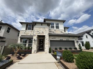 A modern stone-accented home with manicured landscaping in Park Collection At Wolf Ranch by Tri Pointe Homes (Georgetown, TX).