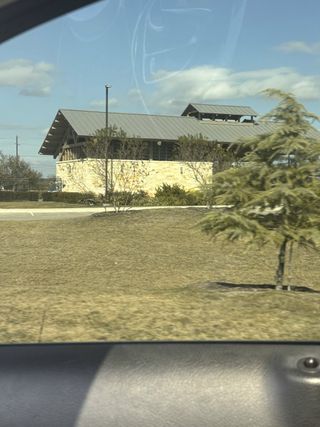 A modern building with a metal roof and stone facade in Katzer Ranch by CastleRock Communities (Converse, TX).