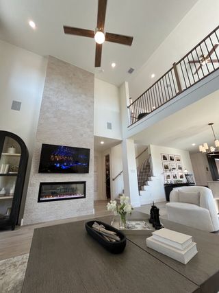 A spacious living area with a high ceiling, stone fireplace, modern decor, and stylish open railing.