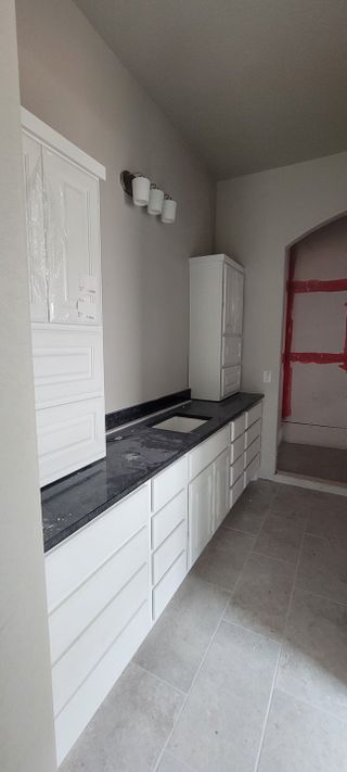 A white bathroom vanity with black countertops and dual sinks. The cabinetry is sleek and modern, with black hardware. 
