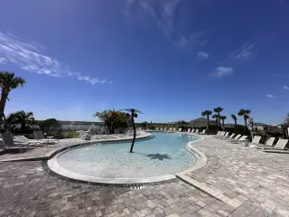 Community Amenities A stunning community pool in Silverlake by Pulte Homes (Lake Alfred, FL), designed for relaxation with resort-style seating and a serene lake backdrop.
