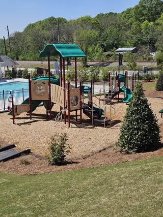 Community Amenities A vibrant playground with slides and a pool area in Diamante by DRB Homes (Stockbridge, GA).