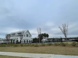Charming white home with a metal roof and landscaped yard in Homecoming by True Homes (Ravenel, SC).