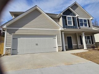Beautiful two-story house with beige siding, blue accent panels, a large garage, and a front porch.