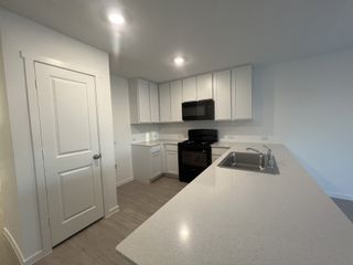 Modern kitchen with sleek black appliances, white cabinets, and a spacious quartz countertop.