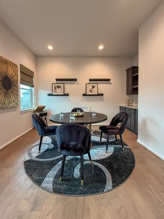 A contemporary dining area with a round table, plush chairs, and modern decor on a patterned circular rug.
