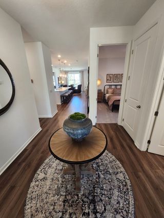Model Home A welcoming hallway with a rustic table centerpiece, cozy bedroom, and elegant kitchen in background with warm lighting.