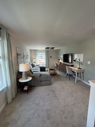 A cozy living space with a plush sectional, a desk, and large windows, creating a bright and inviting atmosphere.