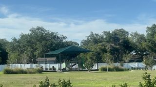 A scenic park setting with a shaded playground in Trinity Place by Trinity Family Builders in St. Cloud, FL.