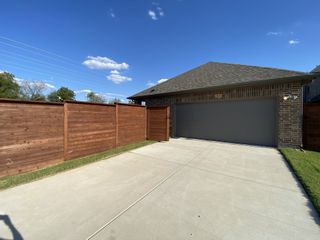 A modern brick home with a spacious driveway and tall wooden fence in Solterra by Impression Homes (Mesquite, TX).