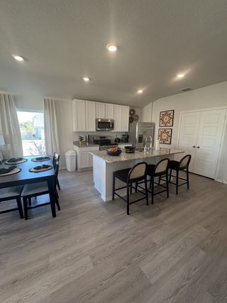A contemporary kitchen with white cabinetry, granite countertops, and an island with barstool seating in Hunters Ranch by Rausch Coleman Homes (San Antonio, TX).