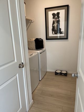 A functional laundry room with modern appliances, wood-style flooring, and a charming dog portrait.