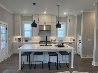 A modern kitchen with sleek white cabinets, pendant lighting, and a spacious island with seating.
