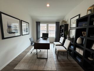 Model Home A sophisticated home office with dark shelving, modern décor, and a large window for natural light.