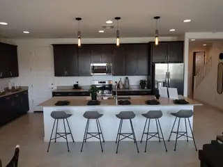 A modern kitchen featuring sleek dark cabinets, stainless steel appliances, and an inviting island with stylish barstools.