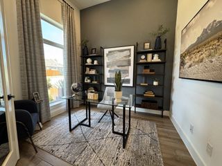 A modern study with a glass desk, stylish shelves, and elegant decor. Cozy ambiance with large windows and tasteful art.